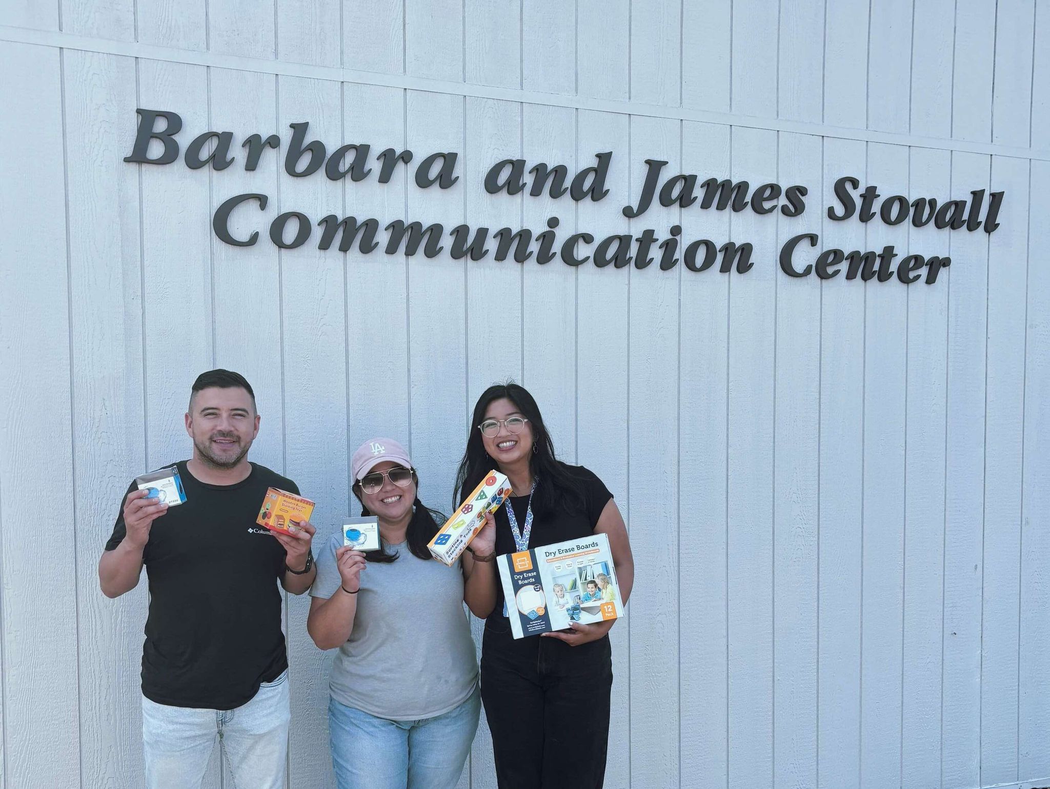 Speech therapists holding supplies in front of the Barbara and James Stowell Communication Center.